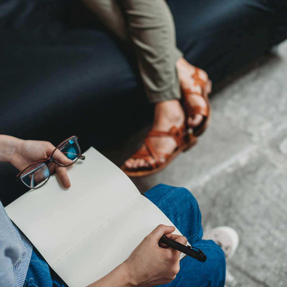 Close-up of a mental health therapy session, featuring a client with a notebook and a therapist listening attentively—representing in-person therapy at Mount North.