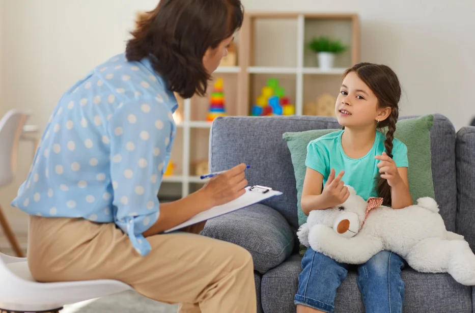 A young girl smiles while speaking with a psychologist during a child-focused psychological evaluation in a custody case.