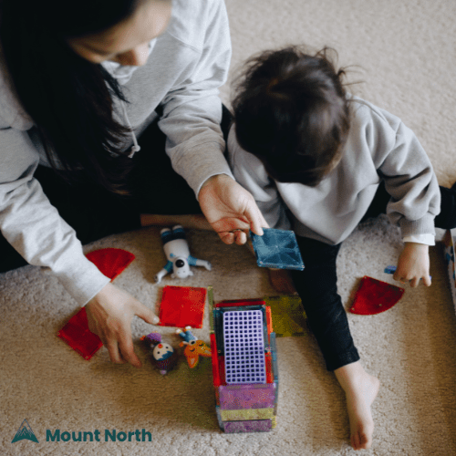 Parenting Support for Neurodivergent Children Mother and child playing with colorful educational toys on carpet