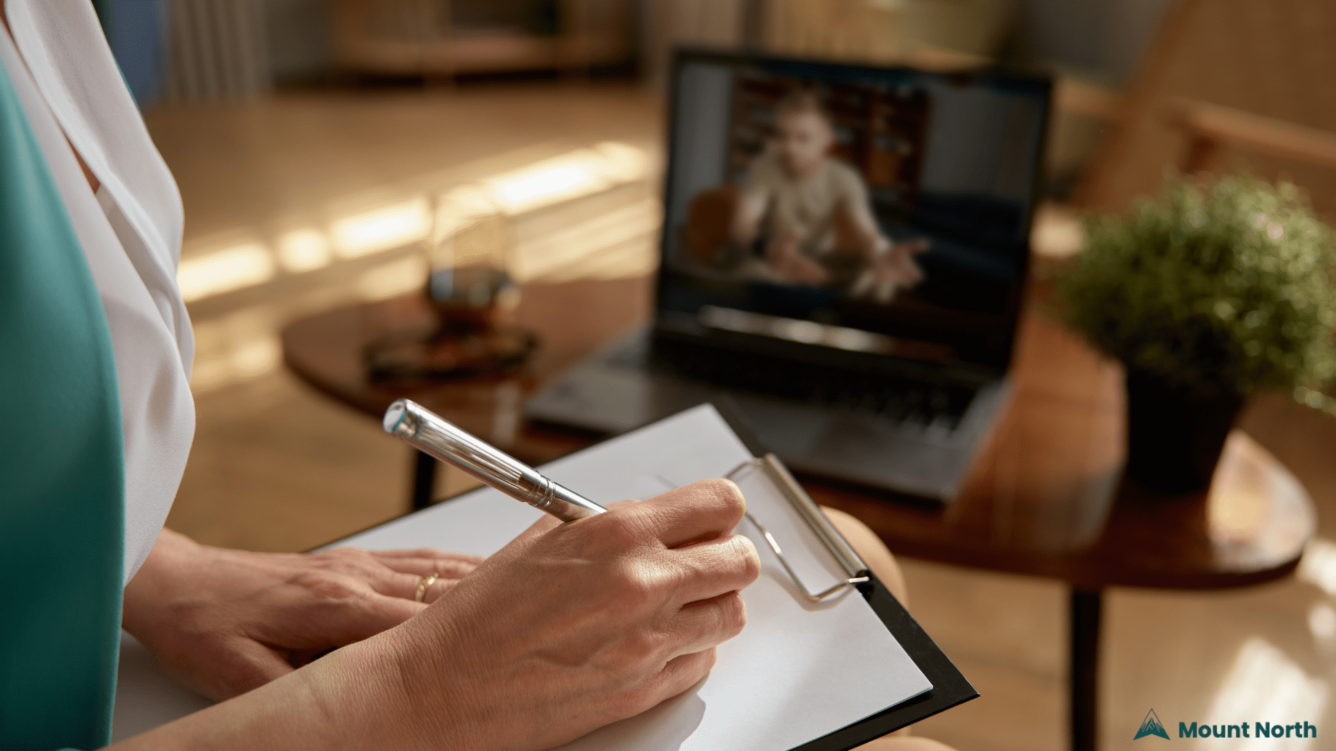 Online Medication Management – Mount North Telehealth Services Close-up of a mental health provider taking notes during a telehealth video session, representing online psychiatric medication management at Mount North.